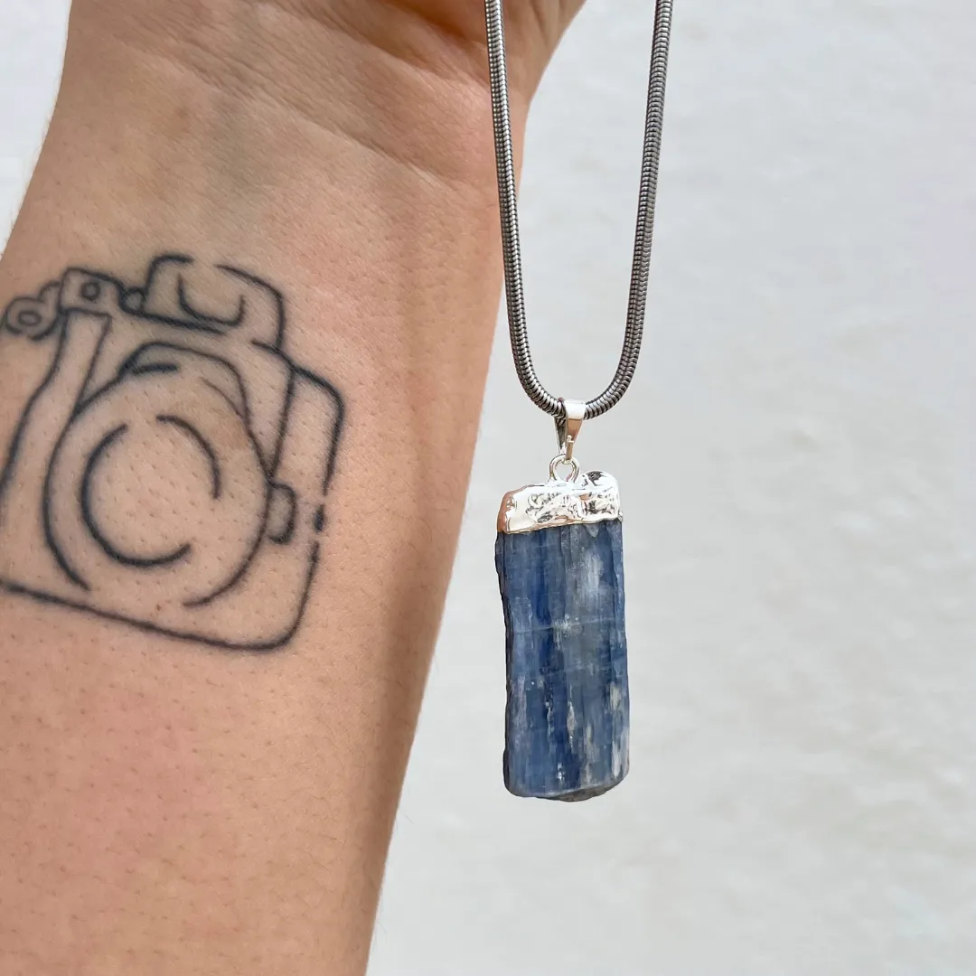 1 ALT: Pendente cianite azul com energia de proteção e alinhamento espiritual Legenda: Proteção e alinhamento Descrição: Pendente de cianite azul associado à proteção energética, alinhamento espiritual e equilíbrio interior. 2 ALT: Pendente cianite azul com cristal natural em tons azuis profundos Legenda: Energia natural da cianite azul Descrição: Cristal cianite azul natural com tonalidades intensas que transmitem calma, clareza e harmonia. 3 ALT: Pendente cianite azul símbolo de comunicação e clareza mental Legenda: Comunicação e clareza Descrição: O pendente cianite azul ajuda a estimular comunicação consciente, foco mental e expressão equilibrada. 4 ALT: Pendente cianite azul ligado à meditação e equilíbrio energético Legenda: Meditação e equilíbrio Descrição: Cristal ideal para meditação, alinhamento energético e conexão espiritual profunda. 5 ALT: Pendente cianite azul decorativo com energia harmoniosa e natural Legenda: Harmonia e energia positiva Pendente cianite azul com energia de proteção e alinhamento espiritual